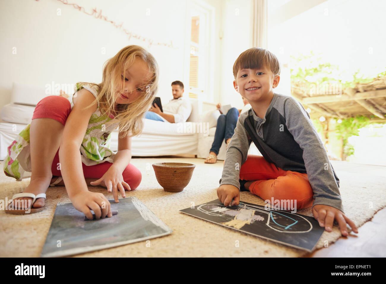 Indoor shot of little children drawing while their father in the ...