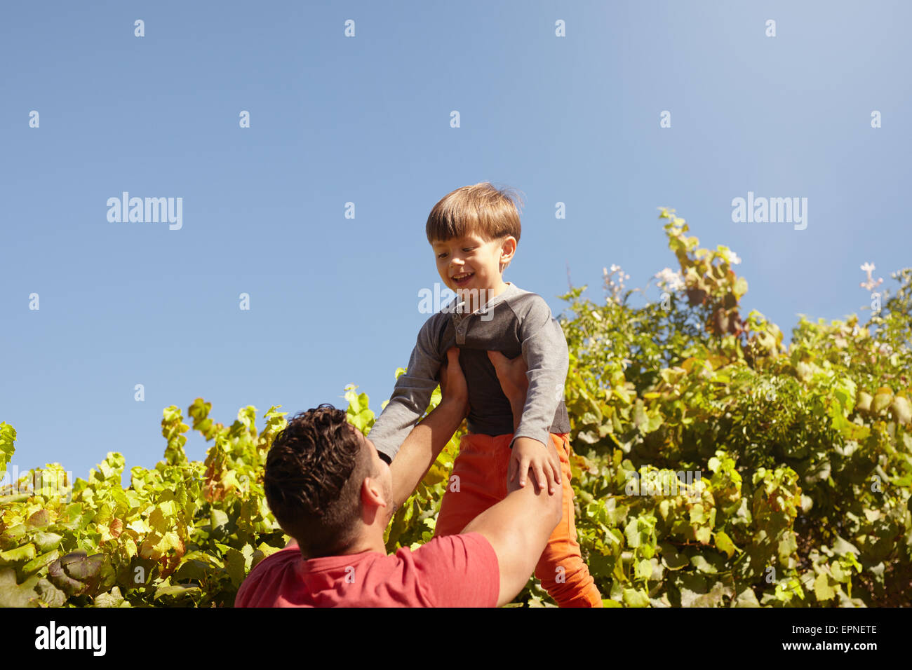 Shot of father lifting his son high in the air. Happy father and son playing outdoors on a sunny day. Stock Photo