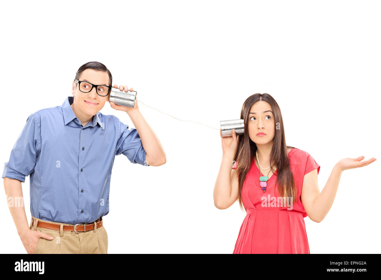Young couple talking through a tin can phone. The woman is gesturing confusion and the man is smiling and listening carefully Stock Photo