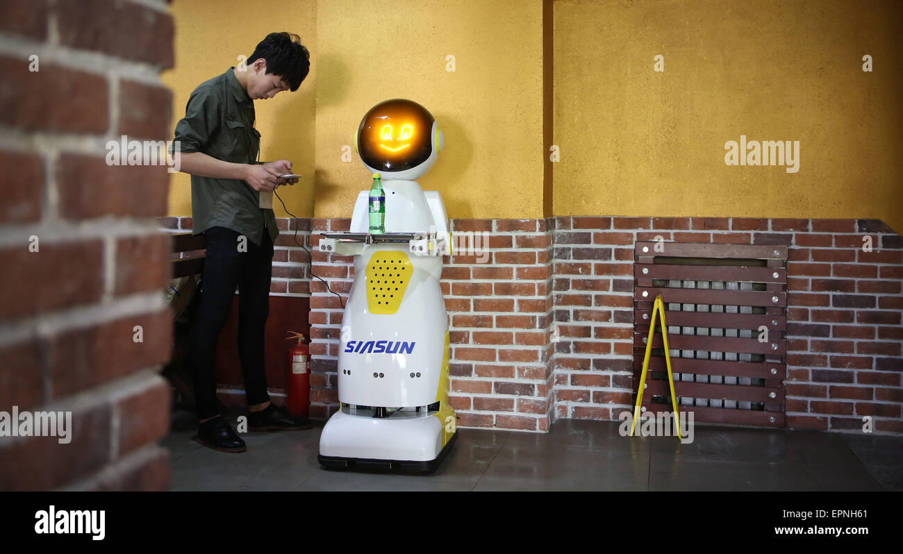 Shenyang, China's Liaoning Province. 20th May, 2015. A staff member sets up a robot in a restaurant in Shenyang, capital of northeast China's Liaoning Province, May 20, 2015. Powered by battery to work up to 7 hours, the 140-centimeter-high robot weights 70 kilograms and moves at a speed of 0.8 meter per second. Integrated with sensors, navigation hardware and user interface technology, it is able to hold and serve up to 8 kilograms of food or beverage at one time. Credit:  Yao Jianfeng/Xinhua/Alamy Live News Stock Photo
