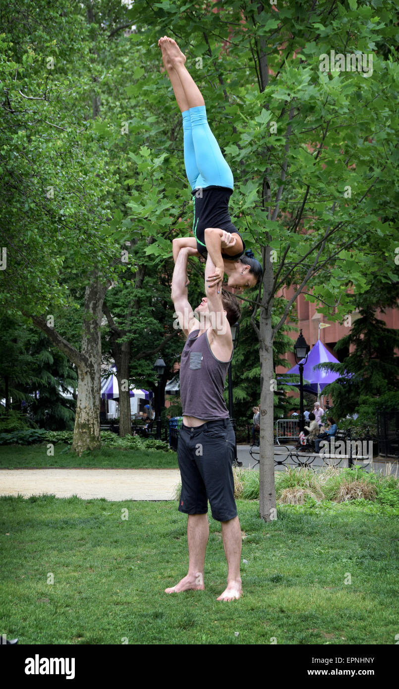 An athletic fit couple do acro yoga exercises in Washington Square Park