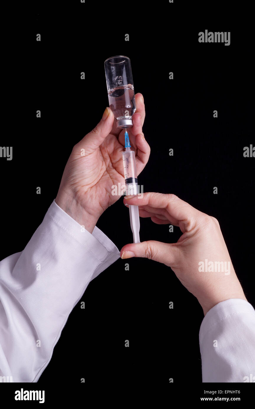 Filling of a syringe with medicine from vial. Medical person holding