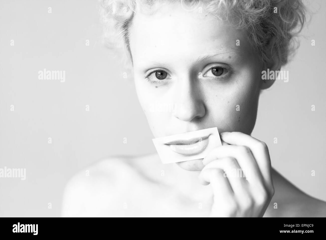 Tender young girl closes her lips to picture painted lips. Black and white photography in bright colors. Stock Photo