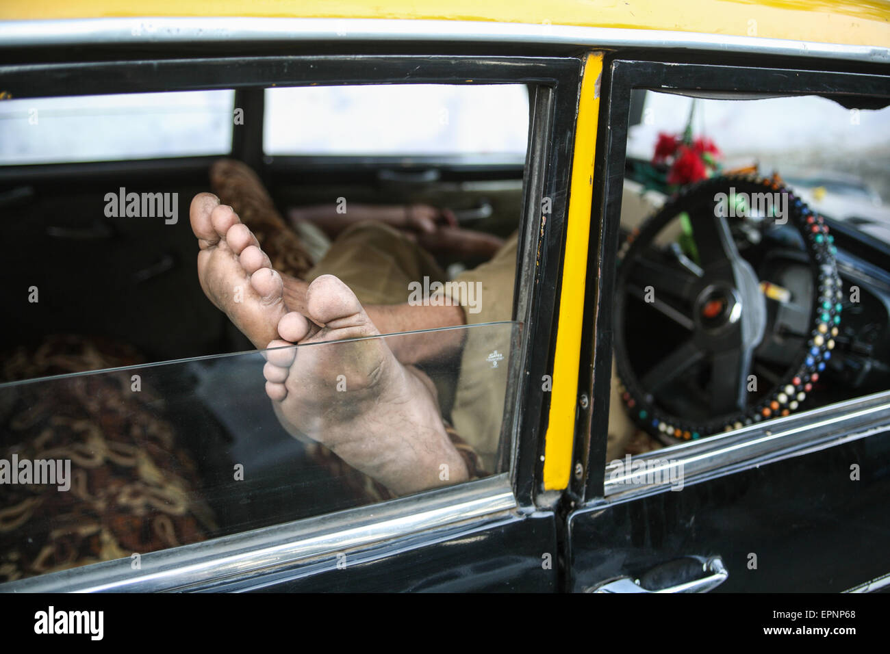 Taxi driver without a passenger fare takes a nap/ sleep in his taxi in Mumbai/ Bombay, India's economic powerhouse and capital o Stock Photo