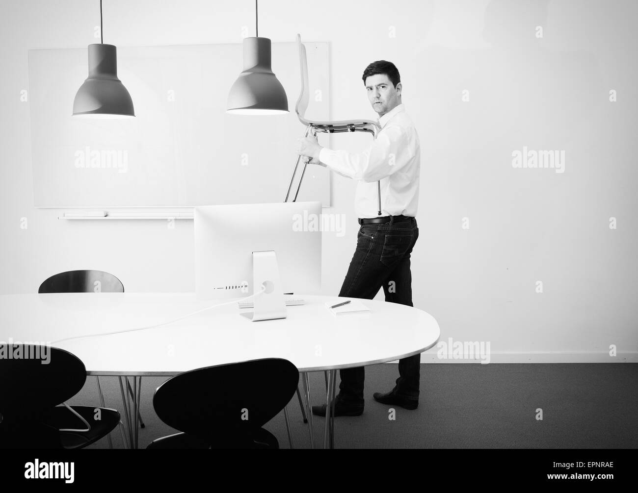 Businessman carrying chair in office. Conceptual image of business relocation, startup or change. Stock Photo