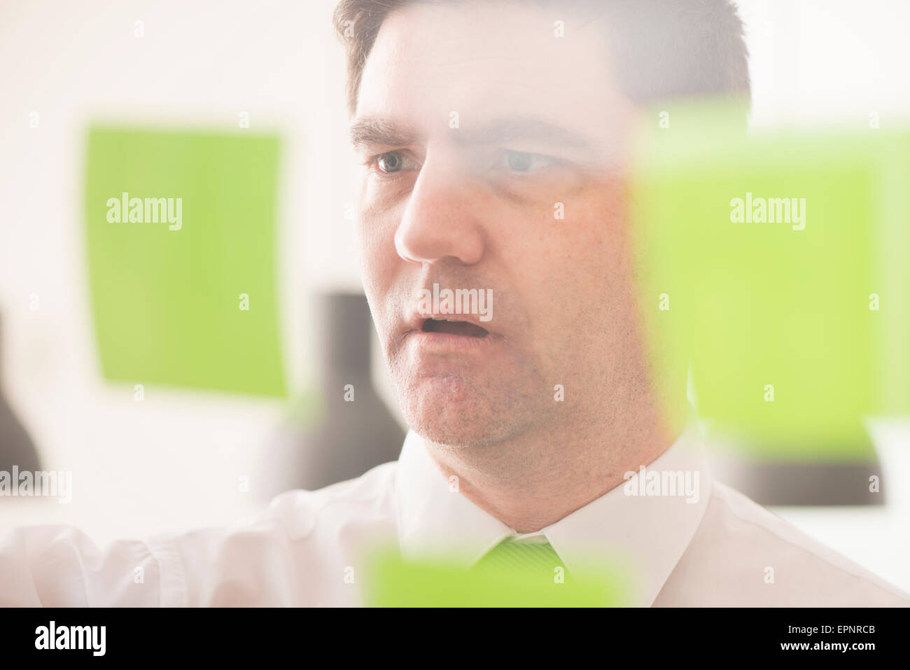 Businessman looking at glass wall with adhesive notes. Conceptual image of business planning. Stock Photo