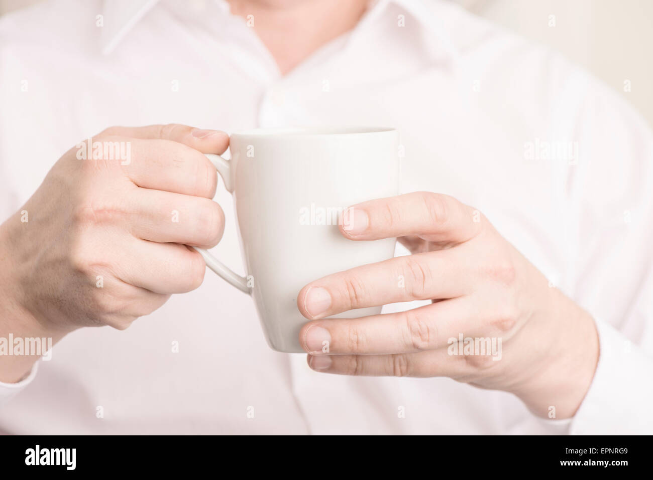 Close up of man holding a white coffee cup with his hands. Stock Photo