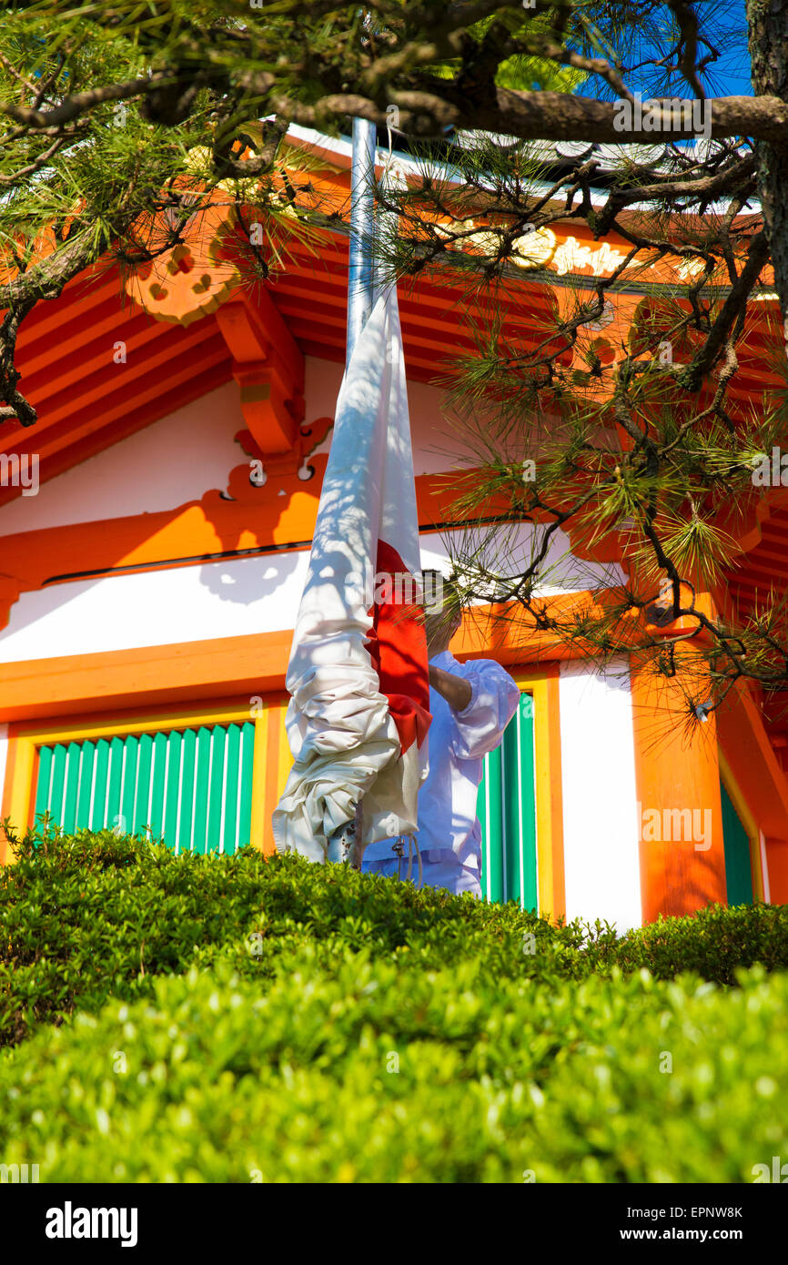 Man raising the Japanese flag up a pole Stock Photo
