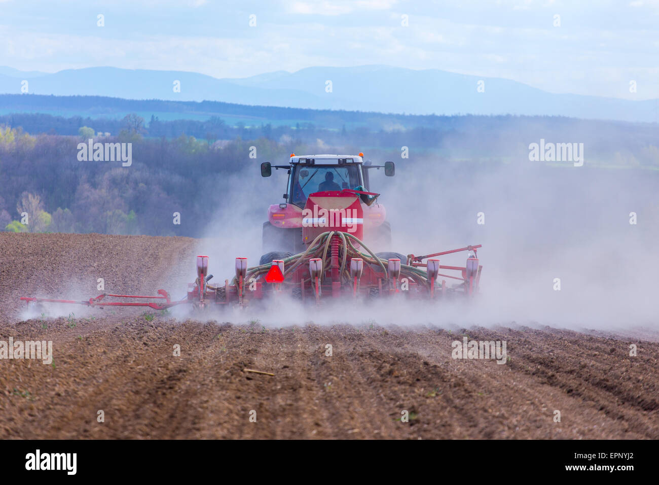 The tractor harrowing the large brown field in spring season Stock ...