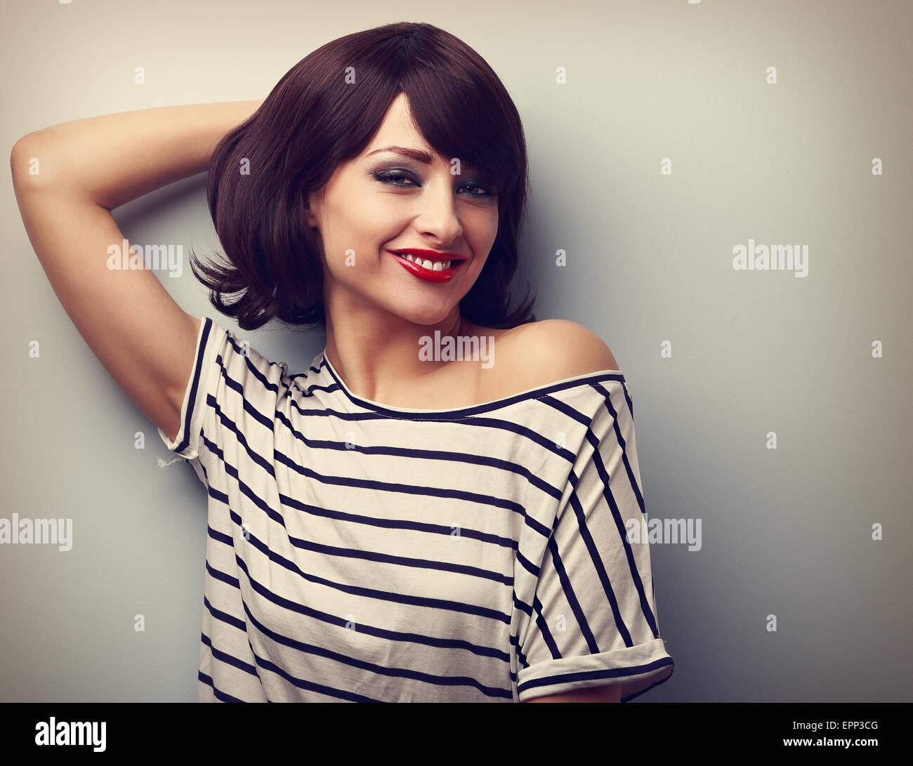 Smiling happy young woman in casual dress relaxing on wall background. Vintage closeup portrait Stock Photo