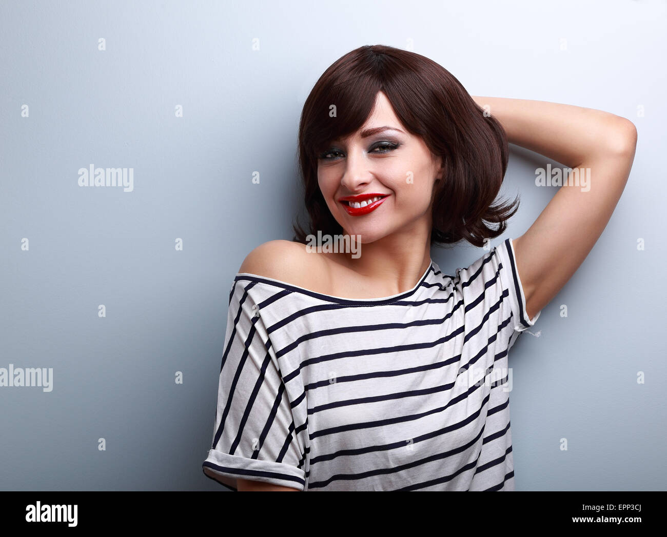 Smiling happy young woman in casual dress relaxing on blue wall background Stock Photo