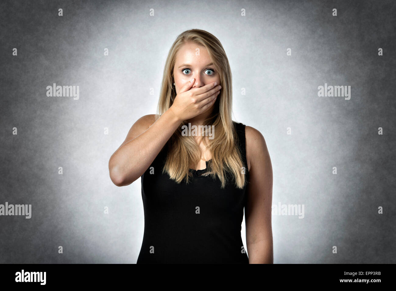Blonde shocked woman holding anxiously the hand over mouth Stock Photo