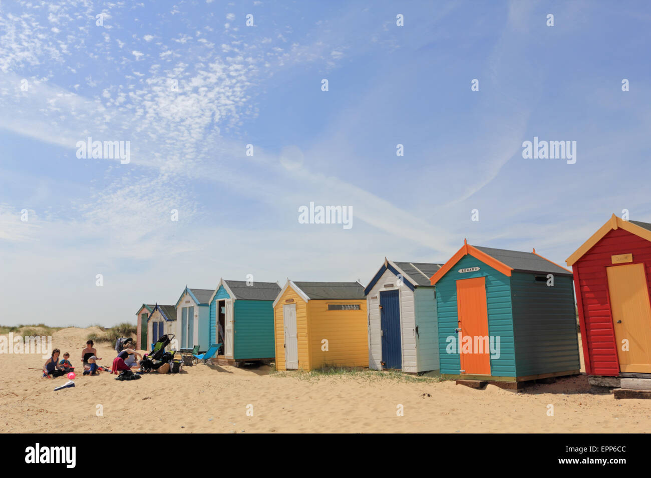 Family sitting in front of Beach Huts at Southwold, Suffolk, England, UK. Stock Photo