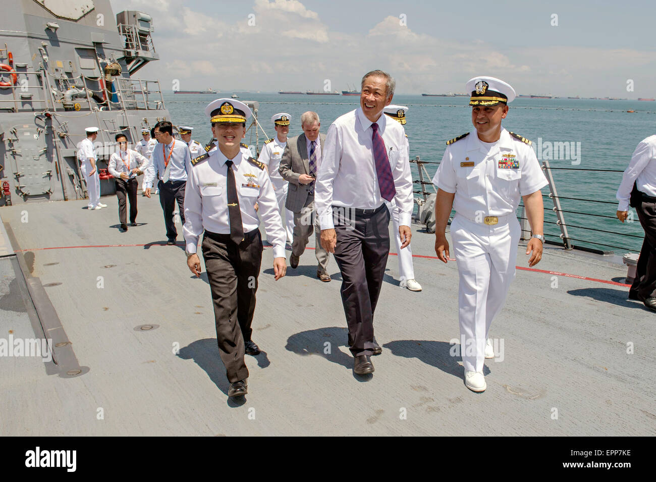 U.S. Navy Cmdr. Joseph Torres, right, escorts Singapore Minister of Defence Dr. Ng Eng Hen, center, during a tour of the Arleigh Burke-class guided missile destroyer USS Mustin May 19, 2015 in Singapore. The Mustin is participating in Singapore's International Maritime Defence Exhibition along with other U.S. Navy vessels. Stock Photo