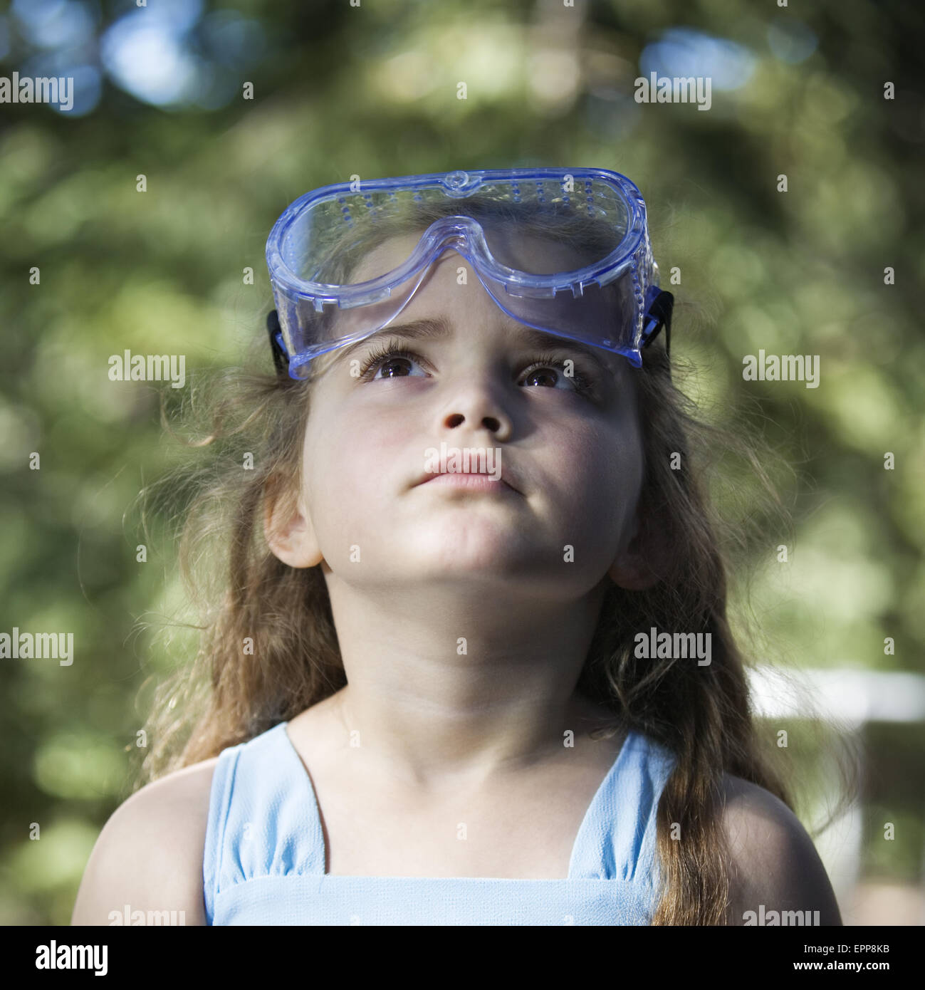 Front view portrait of a young girl looking up with safety goggles on