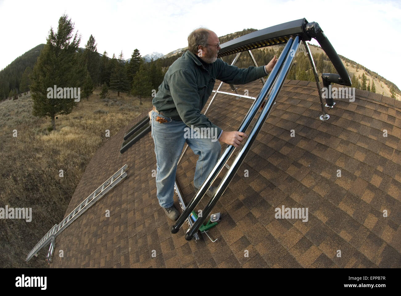 A workman installs a solar hot water system. Stock Photo