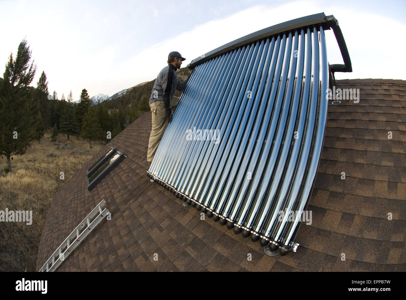 A workman installs a solar hot water system. Stock Photo