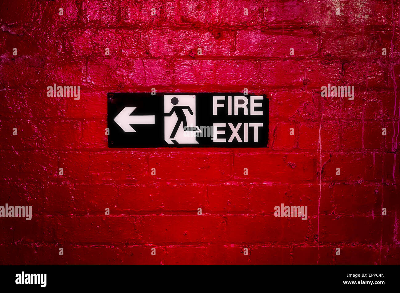 Sign Informing about the fire escape hung on a brick wall painted red. Stock Photo
