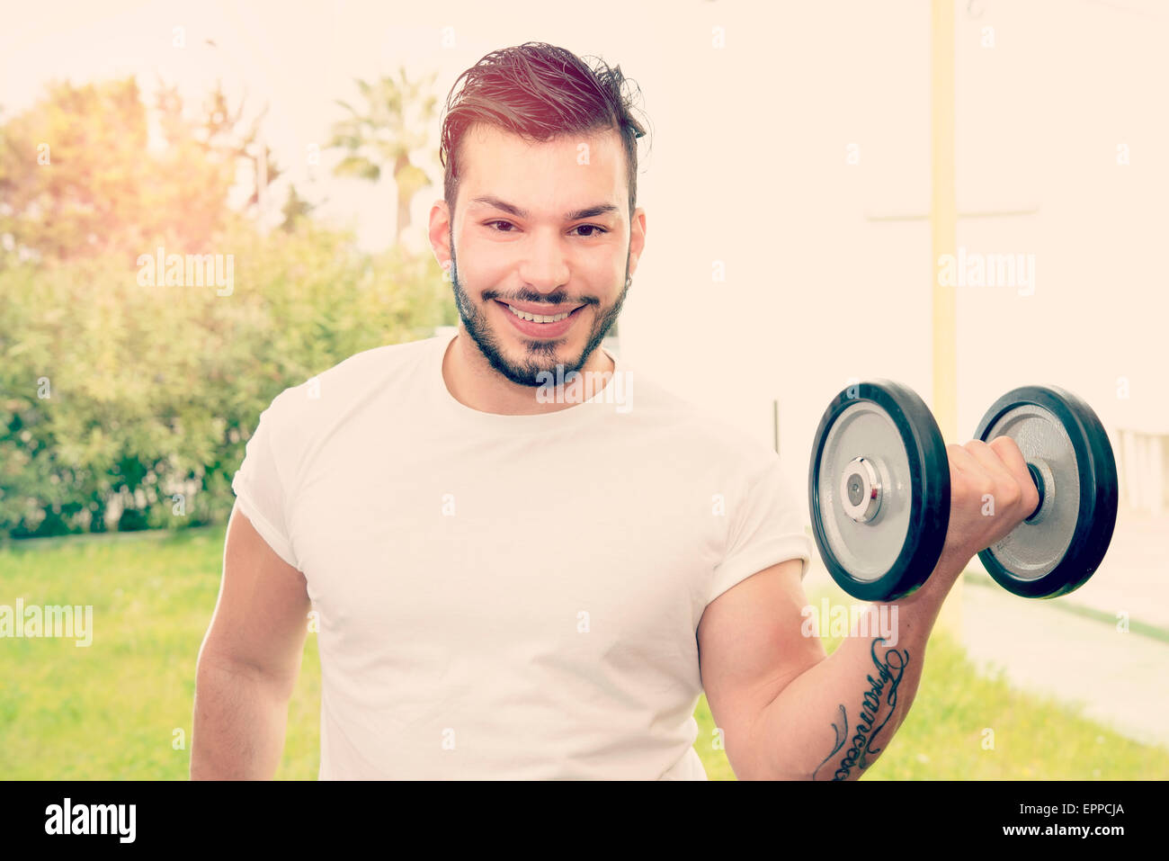 a smiling young man during his fitness exercises outdoors warm filter applied Stock Photo