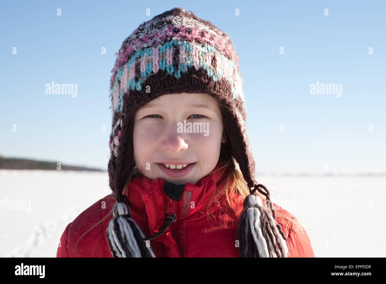 young girl in knitted cap on white snow field and blue sky background Stock Photo