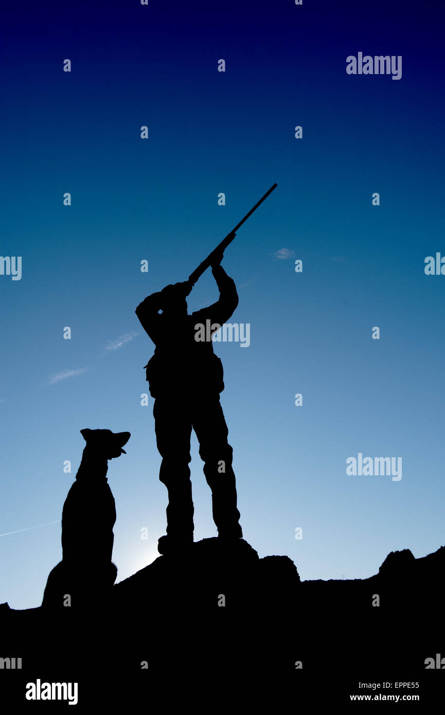 A hunter aims his shotgun with his dog beside him Nevada Stock Photo