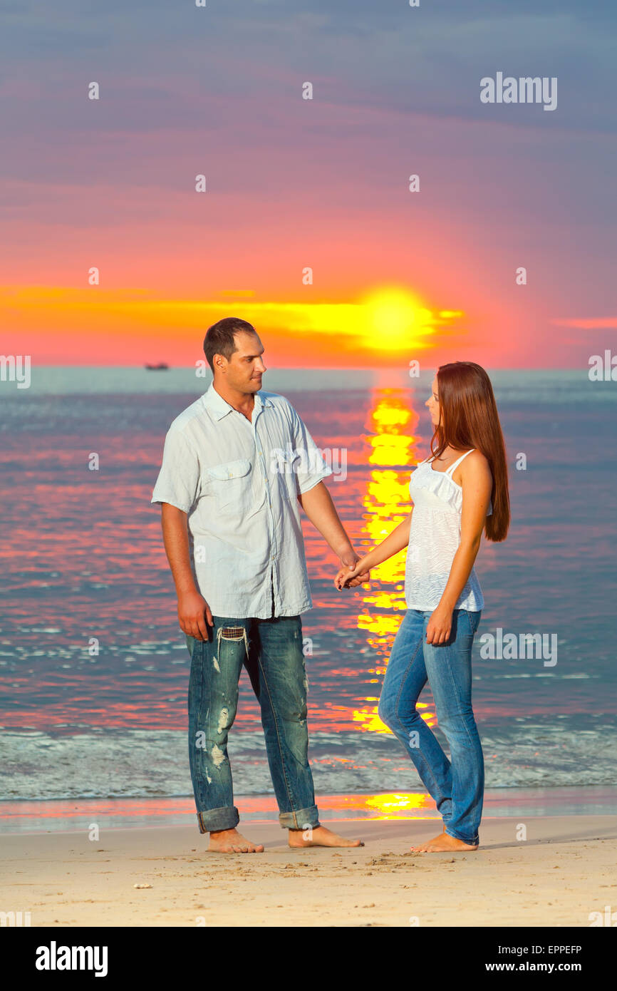 Young couple near the sea at sunrise Stock Photo