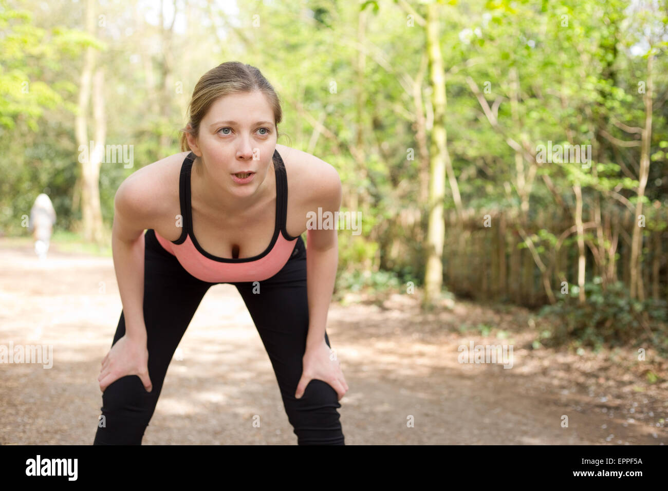 young woman catching her breath while out running Stock Photo