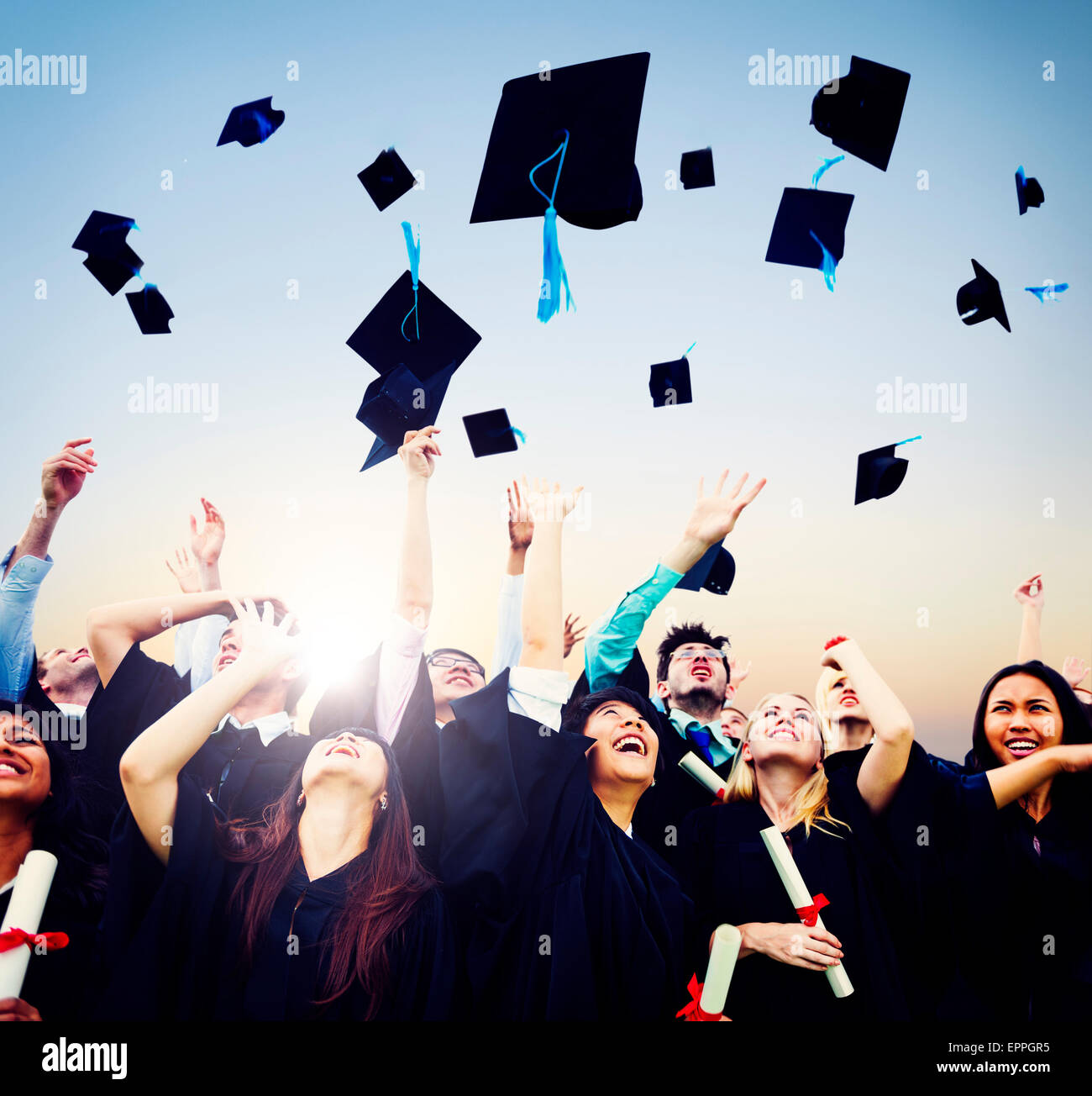 Cheerful students throwing graduation caps in the Air Stock Photo