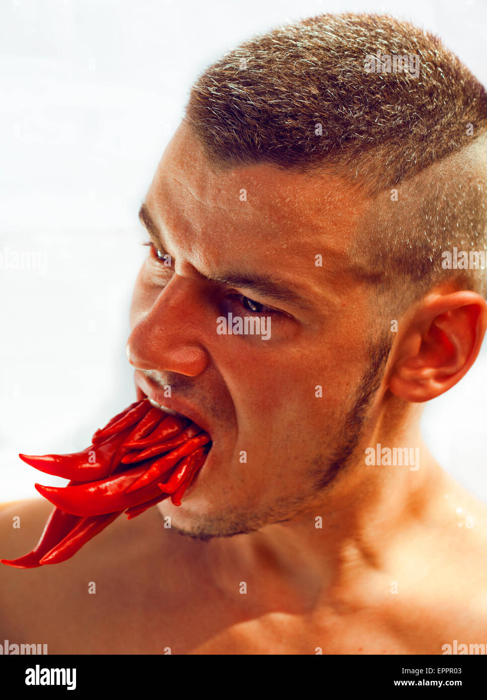 desperate young man with a lot of chilli pepper in mouth, lookin Stock Photo