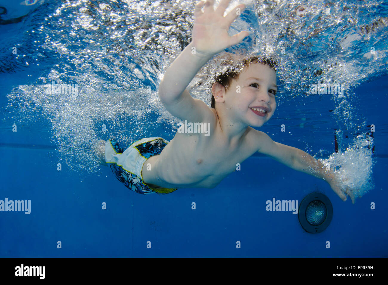 Young boy holds her breath while floating underwater Stock Photo