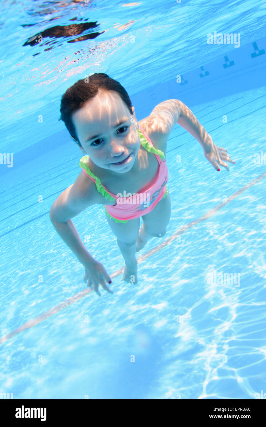 Young girl holds her breath while floating underwater Stock Photo