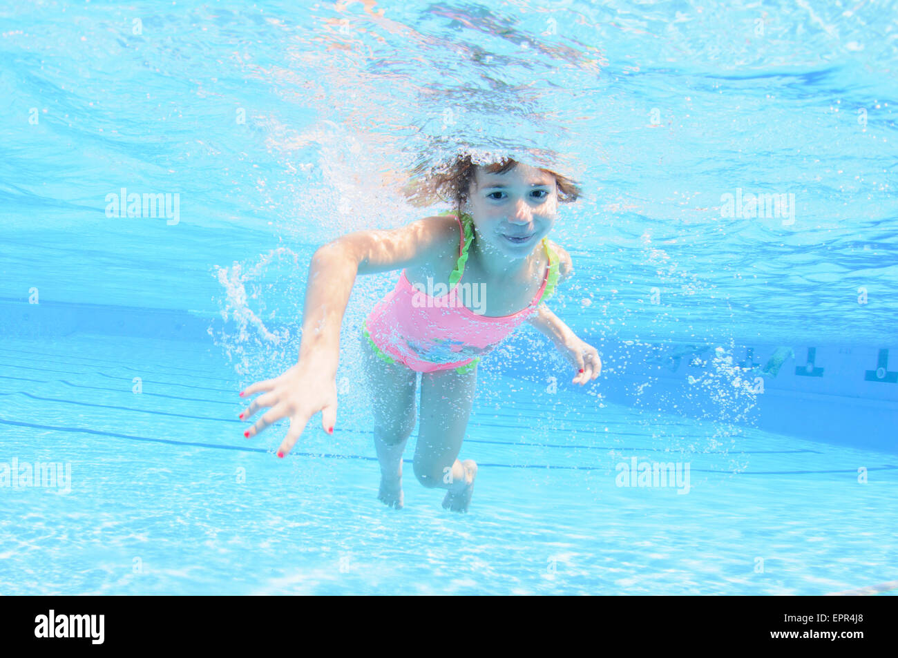 Young girl holds her breath while floating underwater Stock Photo