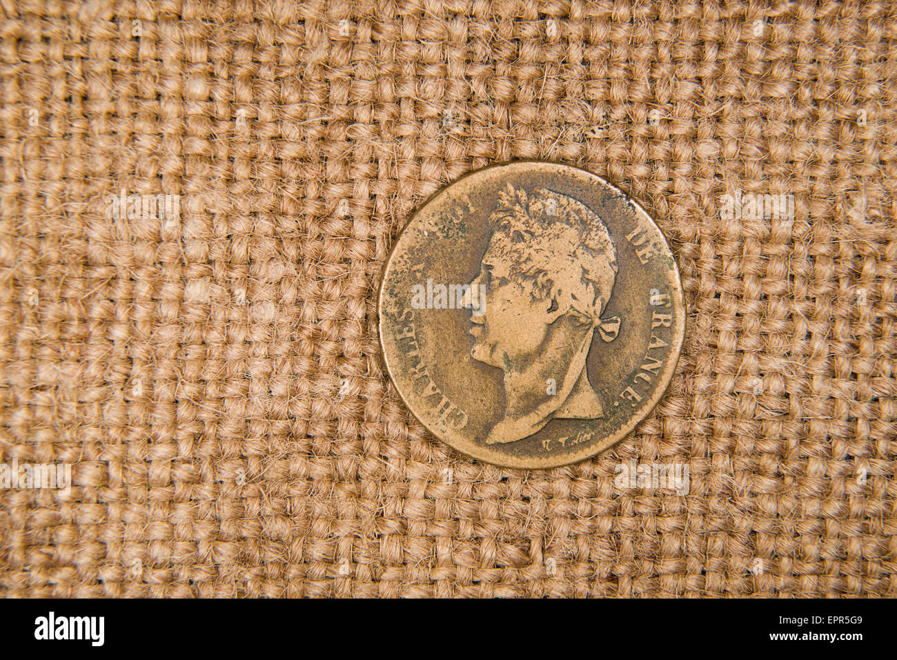 A lot of old bronze coin with portrait of king on the old cloth Stock Photo