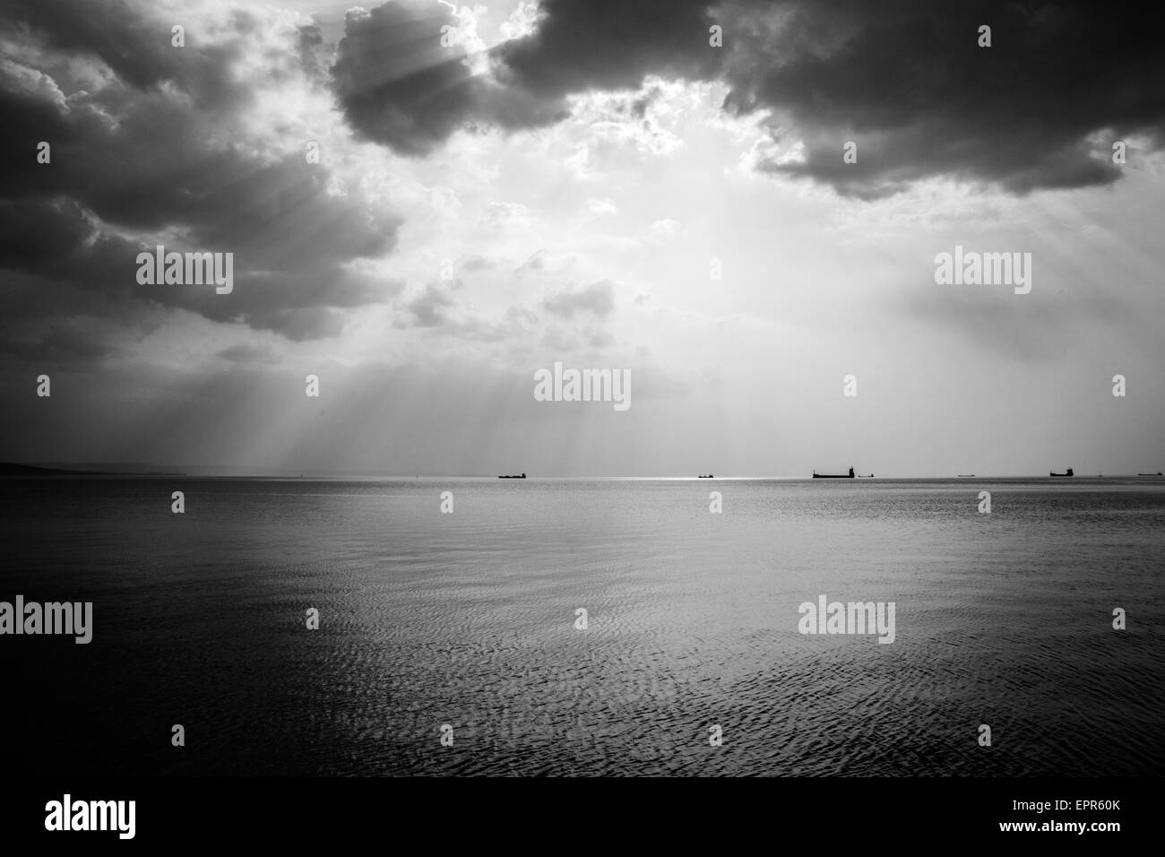 Scattered clouds produce beautiful rays of sunlight over the ships entering and leaving trieste Bay, Italy. Stock Photo