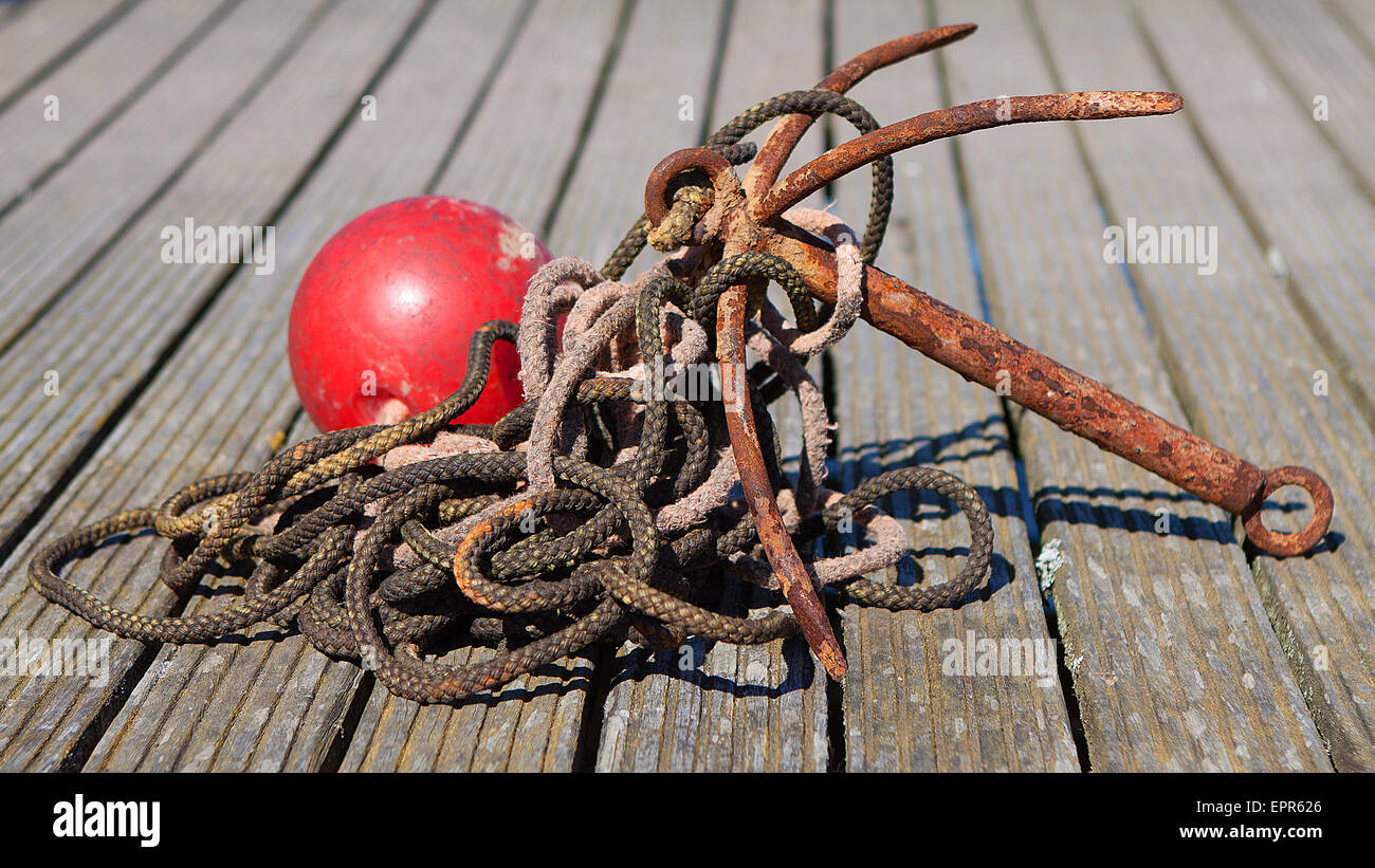 Old anchor and rope on wooden pier Stock Photo