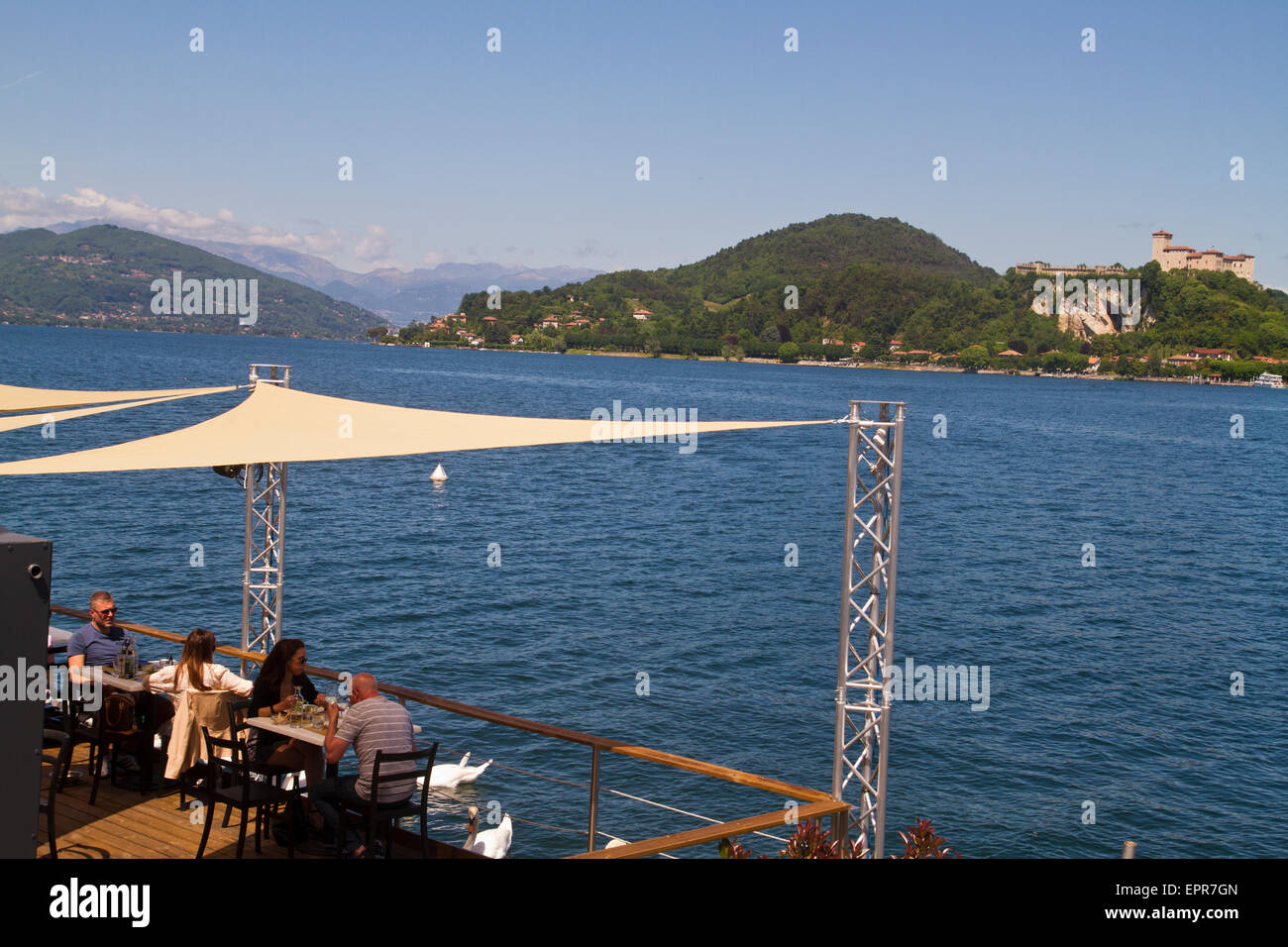 tourists eating at a lakeside restaurant in Arona, Lake Maggiore, Italy Stock Photo