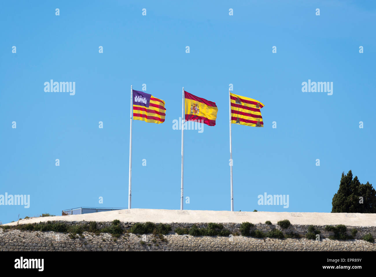three flag waving on top of the city of Ibiza Stock Photo