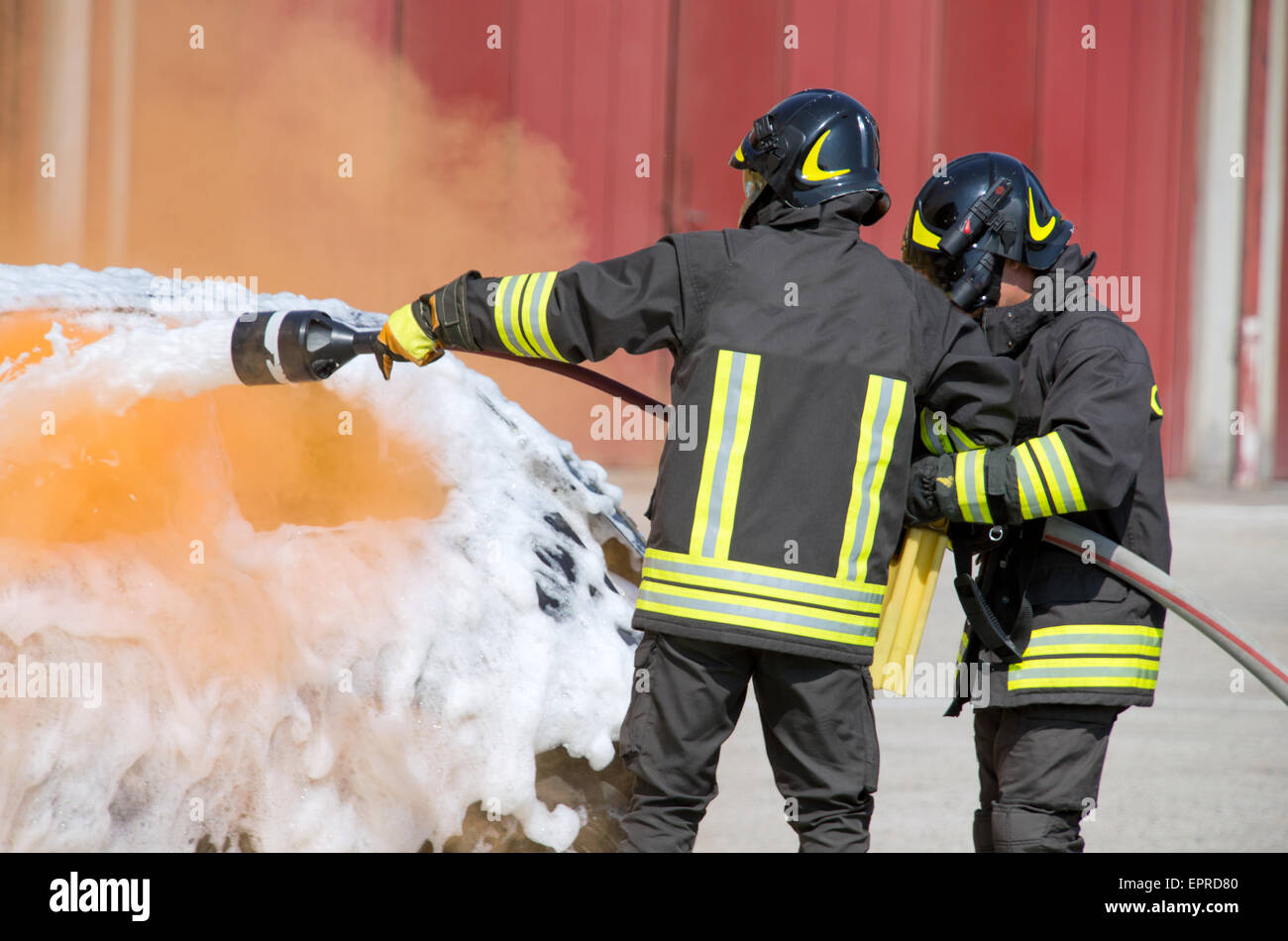 firefighters in action with foam to put out the fire of the car Stock Photo