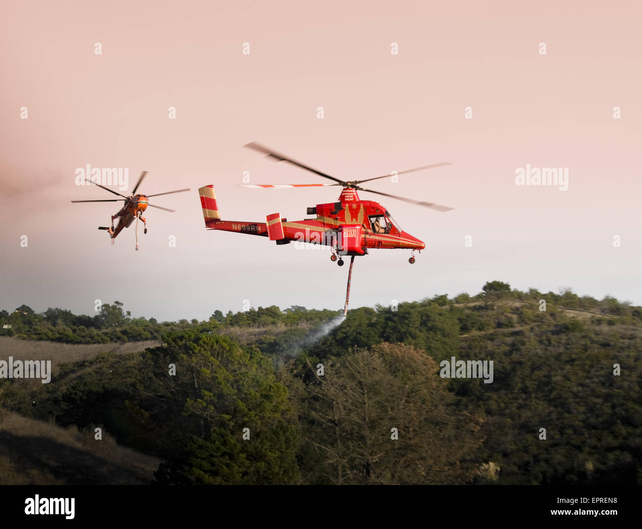 Helicopters pick up water from a reservoir while fighting wildfires in