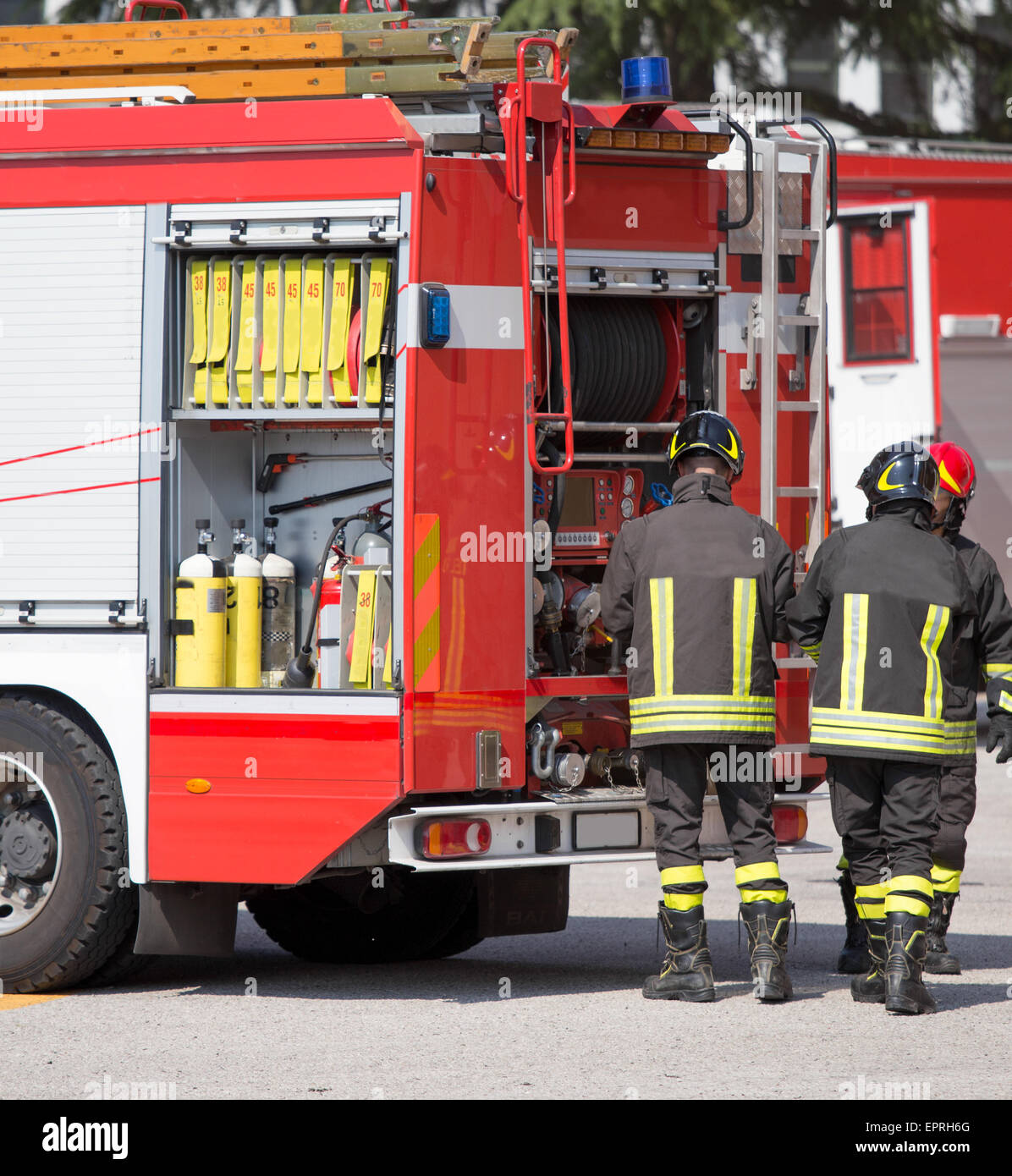 three firefighters and fire trucks during an emergency Stock Photo