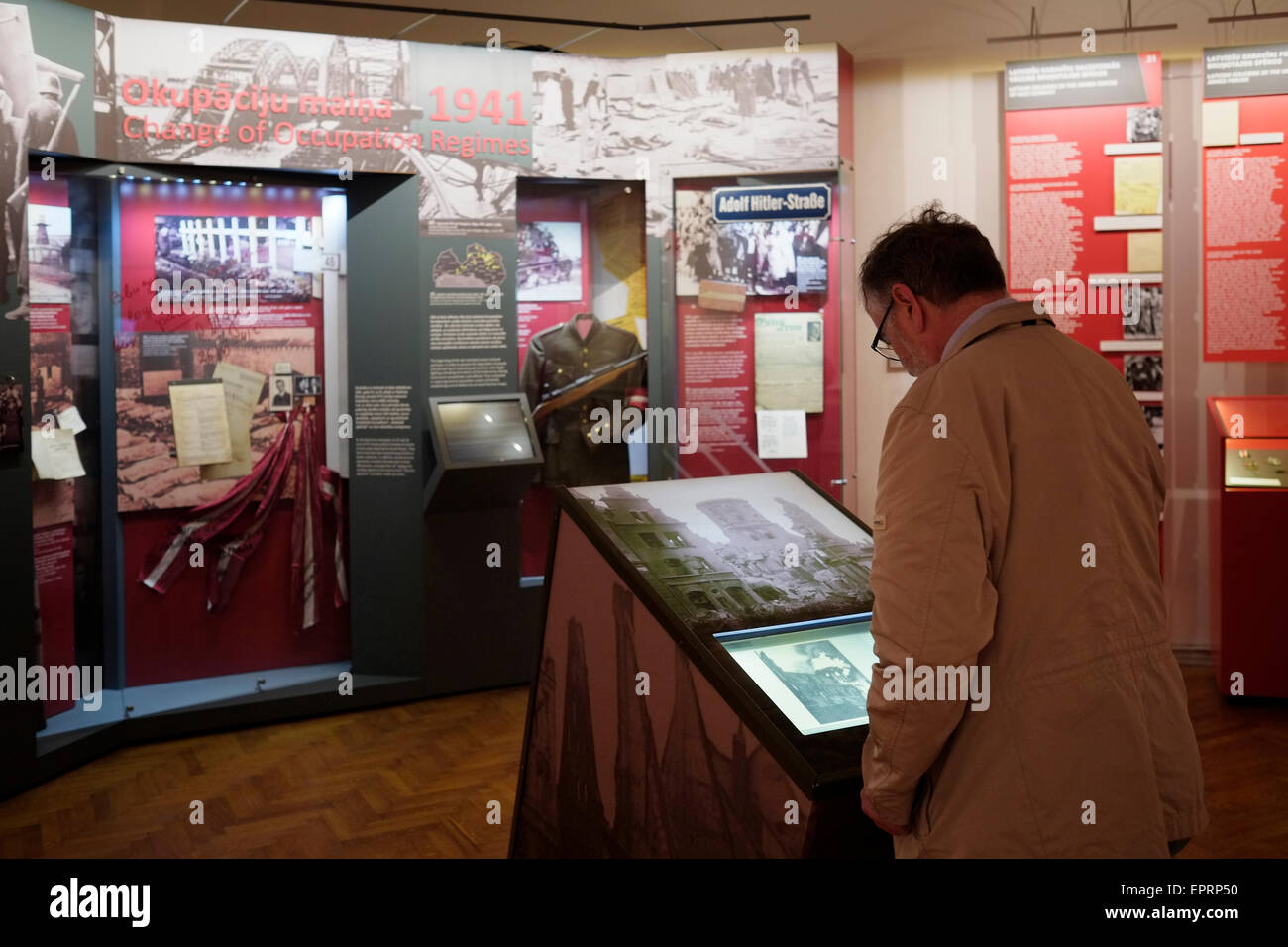 A visitor looking at an old photograph in the Museum of the Occupation of Latvia a historic educational institution established in 1993 to exhibit artifacts, archive documents, and educate the public about the 51-year period in the 20th century when Latvia was successively occupied by the USSR in 1940–1941, then by Nazi Germany in 1941–1944, and then again by the USSR in 1944–1991 located in the city of Riga capital of Republic of Latvia Stock Photo