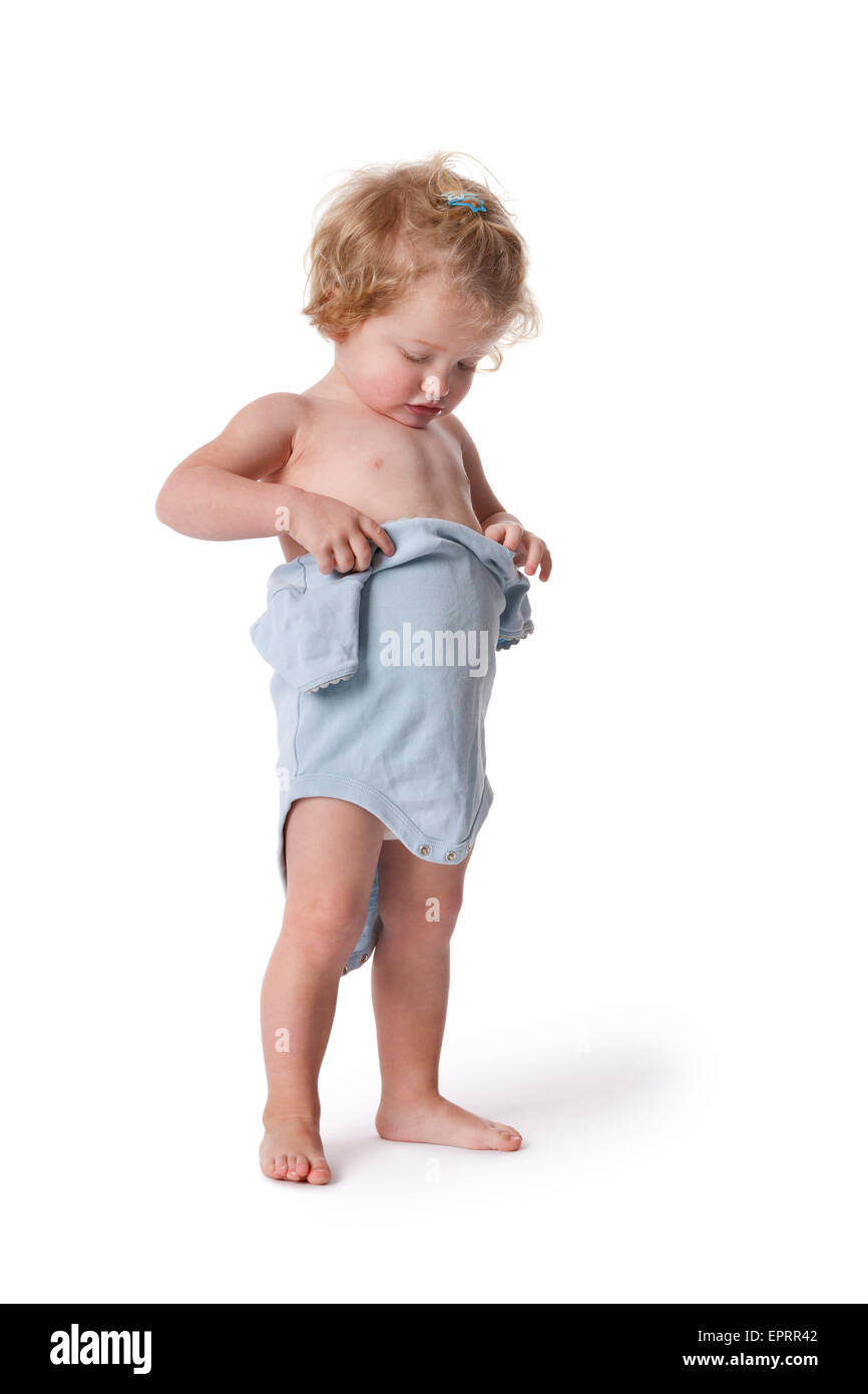 Two year old blond girl trying to put on her infant bodysuit on white