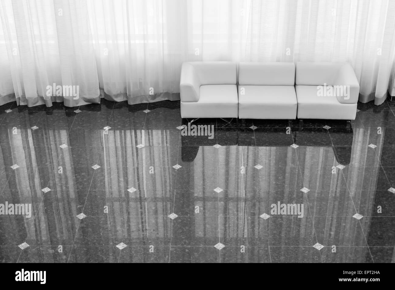 Modern sofas reflected on tiling with huge curtain and ornate floor Stock Photo