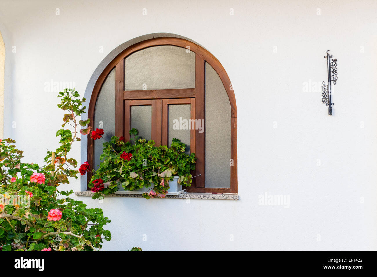 https://c8.alamy.com/comp/EPT422/rounded-wood-frame-window-with-red-geraniums-flower-pots-and-black-EPT422.jpg