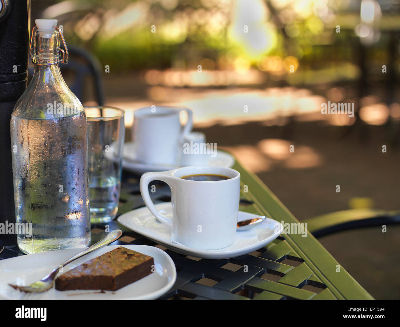 Coffee in white cups and saucers, water bottle and glass with chocolate  brownie on plate at outdoor patio, Canada Stock Photo - Alamy