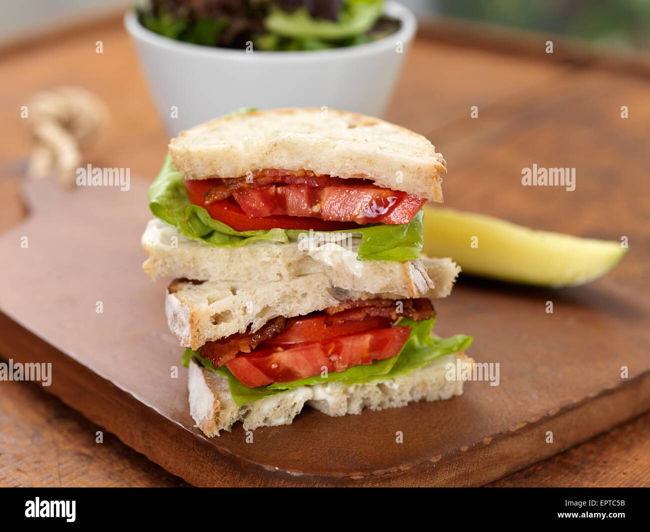 Bacon Lettuce and Tomato Sandwich with Pickle and Salad on Breadboard, Studio Shot Stock Photo