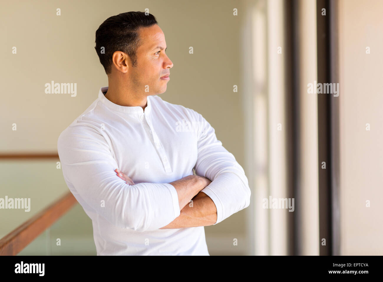 thoughtful mid age man with arms crossed at home Stock Photo