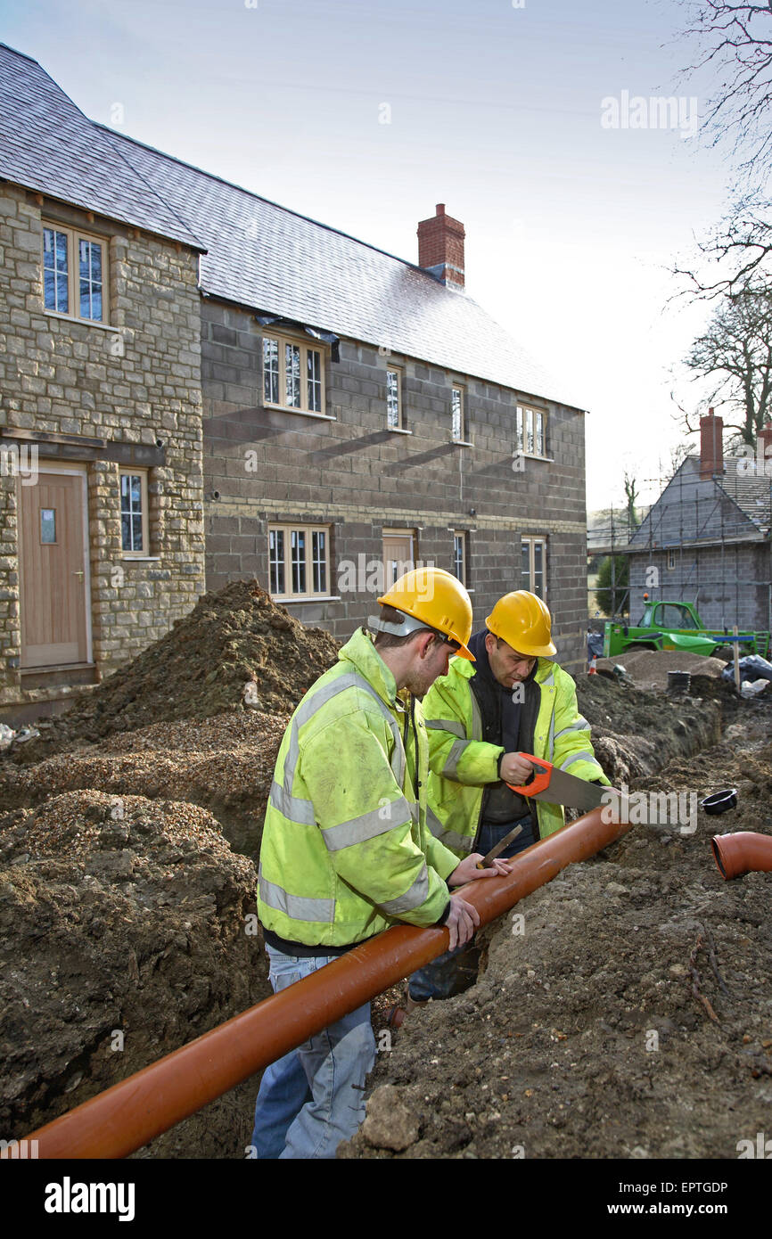 Construction workers cut pipes for the drainage installation on a small, rural housing development in Dorset, UK Stock Photo