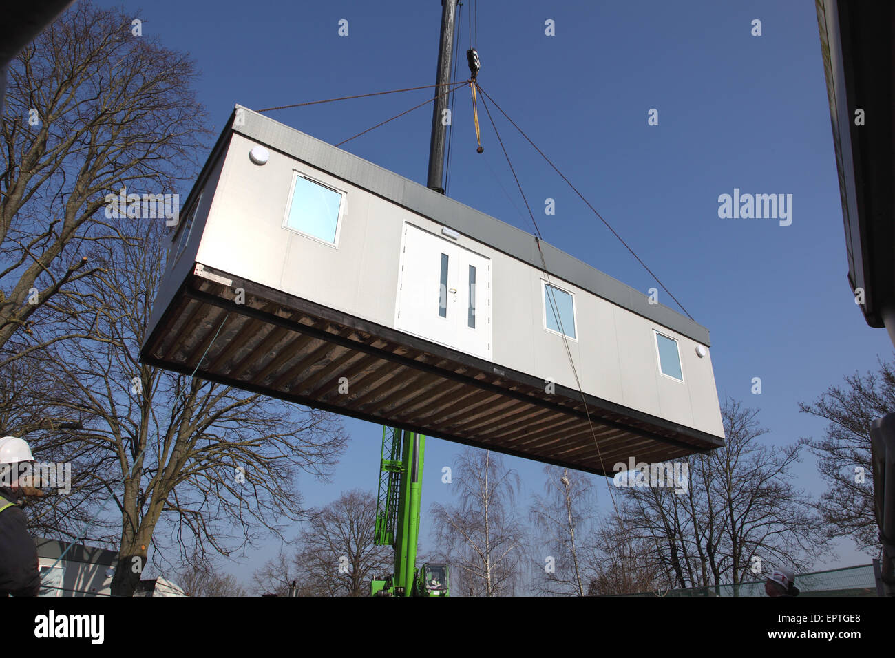 A section of a modular building hangs from a mobile crane during the installation of a new 2-section building. Stock Photo