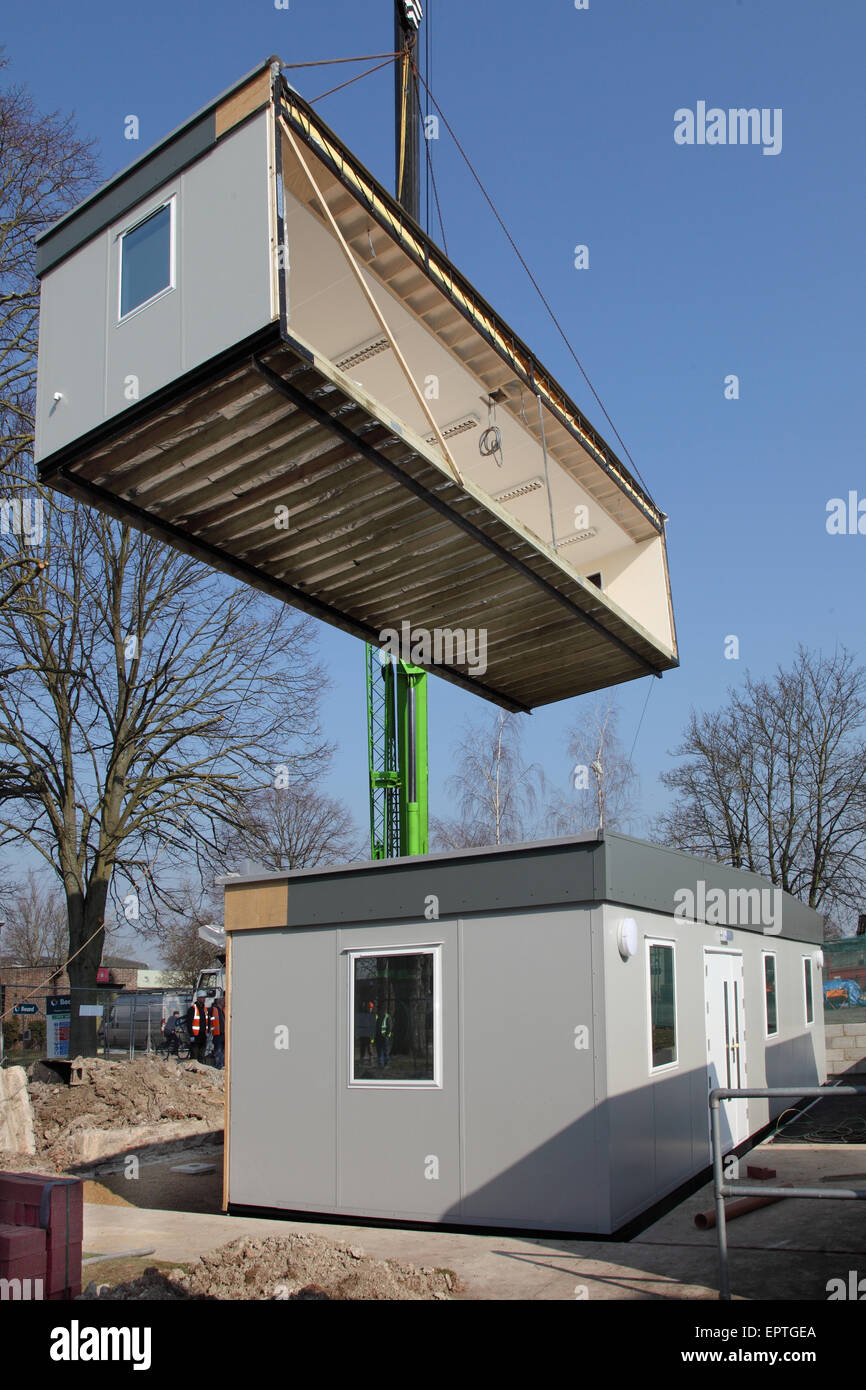A section of a modular building hangs from a crane during the installation of a new 2-section building. Stock Photo
